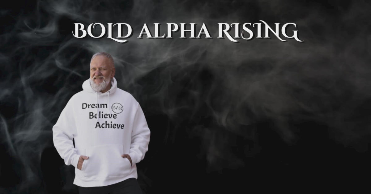 Load video: Image of one of our classic models wearing a sleek white hoodie featuring the motivational quote &#39;Dream, Believe, Achieve&#39; boldly displayed on the design. The hoodie also proudly showcases the Bold Alpha Rising (BAR) logo, representing a commitment to ambition, perseverance, and success. The clean white fabric contrasts sharply with the empowering text, making a strong statement of determination and self-belief.